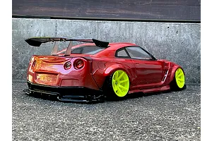 Red RC drift car body featuring a large rear wing and bright yellow wheels, parked on asphalt.