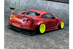 Rear three-quarter view of a metallic red RC drift car body shell on a Nissan GT-R chassis with bright yellow wheels and a large rear wing.