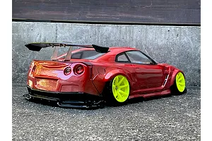 Rear three-quarter view of a painted red RC drift car body on a concrete surface with bright yellow rims and a large rear wing.