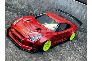 Red RC drift car body styled as a Nissan GT-R with bright green wheels and a rear wing on a concrete surface.