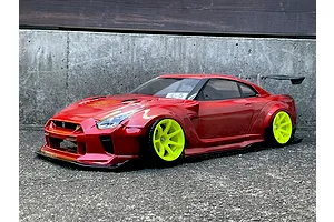 Red RC drift car body shell mounted on a chassis with bright yellow wheels, outdoors on asphalt.