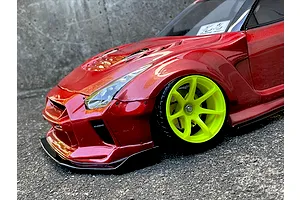 Close-up of a metallic red RC drift car body shell with wide fenders and bright yellow wheels.