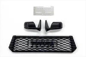 Black plastic RC scale accessories including a front grille with Toyota lettering, side mirrors, and a small decal sheet.