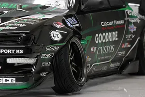 Close-up of the front wheel and fender of a black and green Pandora RC S14 Silvia drift car body with sponsor decals.