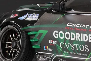Close-up of the front fender and wheel of a black and green Pandora RC S14 Silvia RC drift car body with sponsor decals.