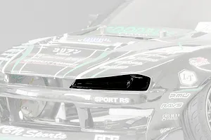 Close-up of a black RC car headlight bucket installed on a detailed model car body with sponsor decals.
