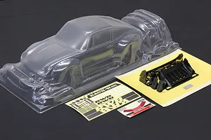 Pandora RC unpainted clear RWB 993 Type body shell with included black plastic parts and decal sheets on dark surface.