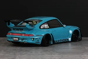 Rear three-quarter view of a bright blue RWB 993 RC drift car body with wide fenders, a large rear wing, and various sponsor decals.