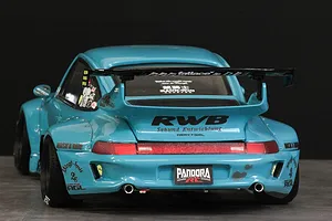 Rear three-quarter view of a light blue Pandora RC RWB 993 Type body shell with wide fenders, spoiler, and decals on a dark studio background.
