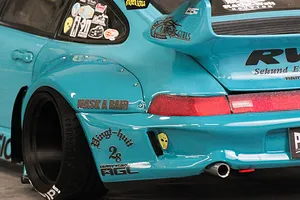 Close up of the rear quarter and wide fender of a light blue RC drift car body with sponsor decals.