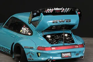 Rear three-quarter view of a light blue RC drift car body shell with a large spoiler and open engine bay, featuring RWB branding.