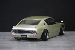 Rear three-quarter view of a gold Pandora RC KPGC110 Skyline 2000GT-R drift body shell mounted on a chassis.