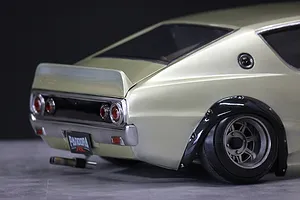 Close-up rear angled view of a custom silver RC drift car body shell showing wheel arches, tail lights, and exhaust.