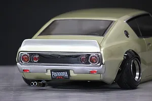 Close-up rear view of a gold Pandora RC KPGC110 Skyline 2000GT-R drift car body shell showing dual exhaust and tail lights.