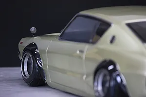 Close-up side profile of a silver RC drift car body shell showing front fender flare, side mirror, and deep dish wheels.