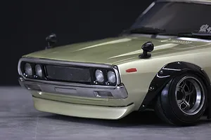 Close-up front view of a painted gold RC car body shell with black fender flares, front spoiler, and detailed grille.