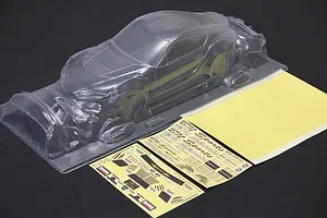 Unpainted clear polycarbonate RC car body shell with separate decal sheets on a dark surface.