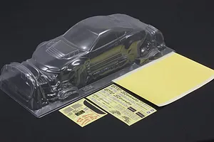 Unpainted clear polycarbonate RC car body shell with separate decal sheets and masking film on a dark surface.