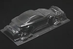 Unpainted clear polycarbonate RC drift car body shell viewed from a rear three-quarter angle against a dark background.