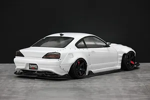 Rear-three-quarter view of a white RC drift car body styled as a Nissan S15 Silvia on a grey surface.