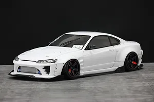 Painted white RC drift car body shell mounted on a chassis, featuring wide fenders, front intercooler, and black wheels against a dark background.