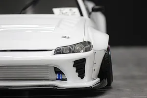 Front-quarter close-up view of a white RC drift car body shell showing detailed headlights, front bumper, and intercooler.