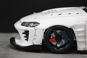 Close-up front quarter view of a white RC drift car body shell showing the front wheel, fender, and bumper details.