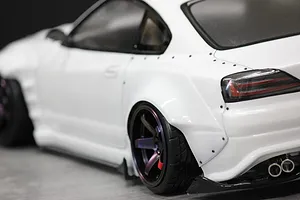 Close-up of the rear quarter, overfender, and wheel of a white RC drift car body on a workbench surface.