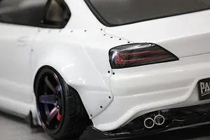 Close-up of the rear quarter, wheel arch, and exhaust of a white RC drift car body shell.
