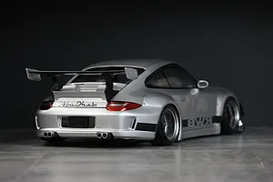 Rear three-quarter view of a silver Pandora RC RWB 997 body shell with a large rear wing and Abu Dhabi branding.