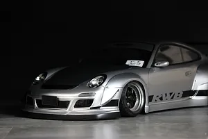 Studio product shot of a silver Pandora RC RWB 997 Type RC body shell featuring wide fenders, black hood, and RWB side graphics against a dark background.