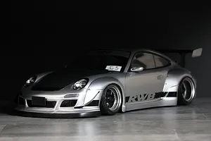 Silver Pandora RC RWB 997 body shell painted and fitted onto an RC drift car chassis, showcasing wide fenders and rear wing.