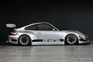 Side profile of a silver Pandora RC RWB 997 Type drift body shell with a large rear wing and black accents on a dark background.