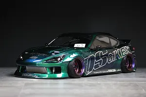 Custom painted green and blue RC drift car body shell mounted on a chassis with deep dish wheels.