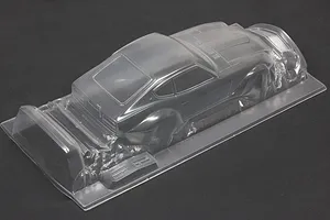 Unpainted clear polycarbonate RC car body shell of a vintage sports car shown from a rear three-quarter angle on a dark surface.