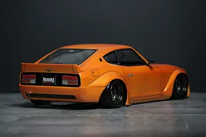 Rear three-quarter view of an orange Pandora RC S30 Fairlady Z Star Road body shell mounted on a chassis, sitting on a grey surface.