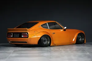 Rear three-quarter view of a painted orange Pandora RC S30 Fairlady Z body shell mounted on a chassis.