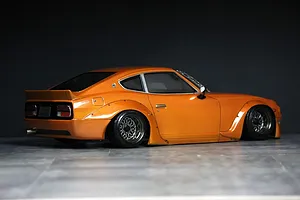 Side-rear view of an orange S30 Fairlady Z RC drift car body shell with detailed wheels and aerodynamic body kit.