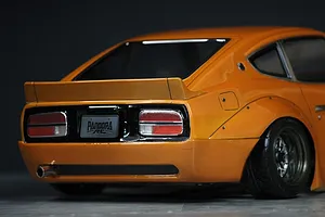 Rear-quarter view of the Pandora RC S30 Fairlady Z body shell in orange with custom wheel fitment and Pandora RC license plate.