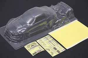 Unpainted clear polycarbonate RC car body shell with separate decal sheets and window masks on a dark surface.