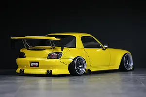 Rear three-quarter view of a yellow Honda S2000 RC drift car body with wide body fenders, large rear wing, and Pandora RC license plate against a dark background.