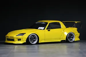 Painted yellow Honda S2000 RC drift car body with wide body kit and rear wing against a dark background.
