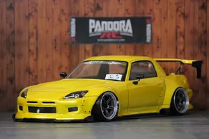 Yellow Honda S2000 RC drift car body shell with custom widebody kit and rear wing parked in front of a Pandora RC sign.