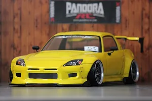 A painted yellow RC drift car body shell mounted on a chassis, featuring a widebody kit, wing, and custom wheels.