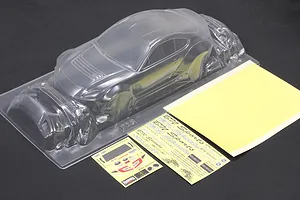Unpainted clear polycarbonate RC car body shell with accessory parts, decal sheets, and window masks on a dark surface.