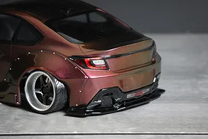 Rear three-quarter close-up of a custom painted RC drift car body showing wide rear fenders, custom wheels, and bumper detail.
