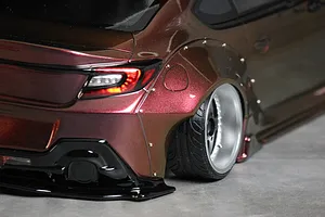 Close-up of the rear quarter and wheel arch of a custom painted RC drift car body with widebody fender flares and deep dish wheels.