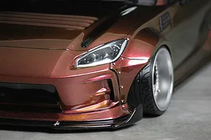 Close-up of the front corner of a custom painted metallic brown RC drift car body with wide fenders and deep dish wheels.