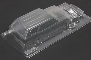 Unpainted clear polycarbonate RC sports wagon body shell shown at an angle on a dark surface.
