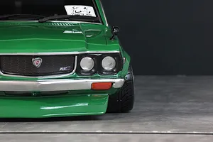Close-up front view of a green RC car body shell showing the grille, headlights, and bumper.